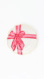 A white scalloped ceramic plate with a gold rim, decorated with a red gift box illustration featuring a red ribbon and bow, shown on a plain white background.