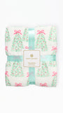 A folded Mary Square fleece blanket featuring a festive Christmas tree pattern with pink bows and ornaments on a white background, wrapped in a mint green ribbon with the brand label in the center.