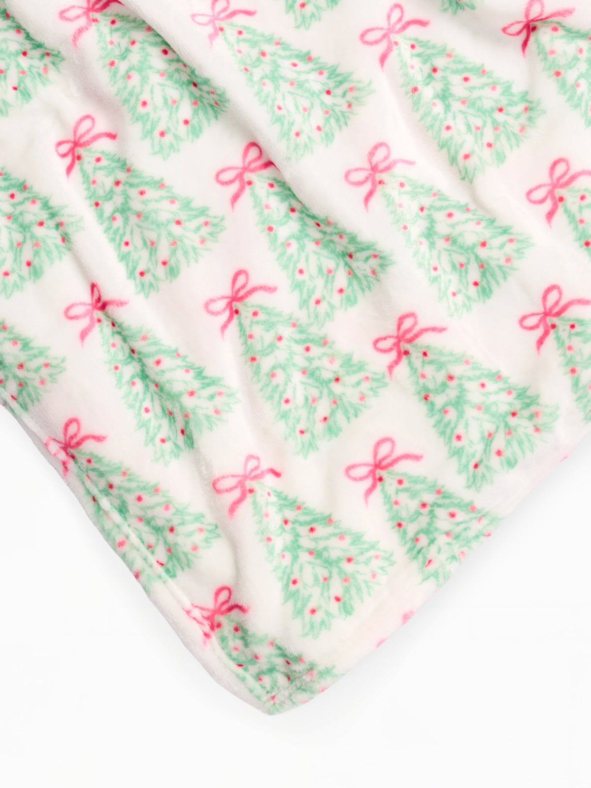 A close-up of a soft white fabric with a repeating Christmas tree print in mint green and pink bows.