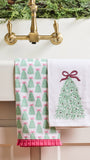 Two white kitchen towels hanging over a brass faucet. One towel has a repeating green Christmas tree pattern with pink bows, and the other has a single large green Christmas tree design with a pink bow on the right side.