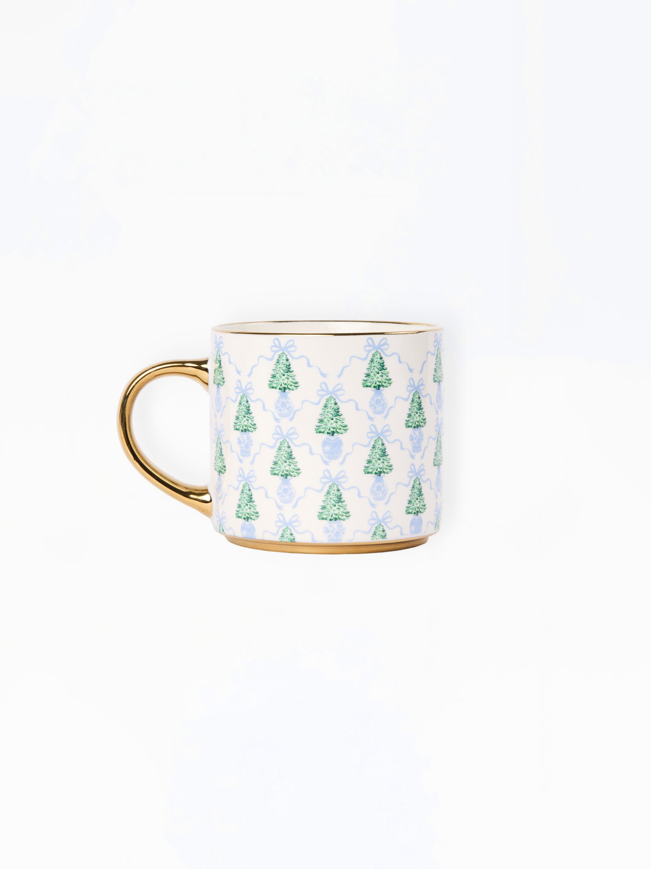 A white ceramic mug with a gold handle and base trim, decorated with a repeating pattern of green Christmas trees and light blue damask motifs.