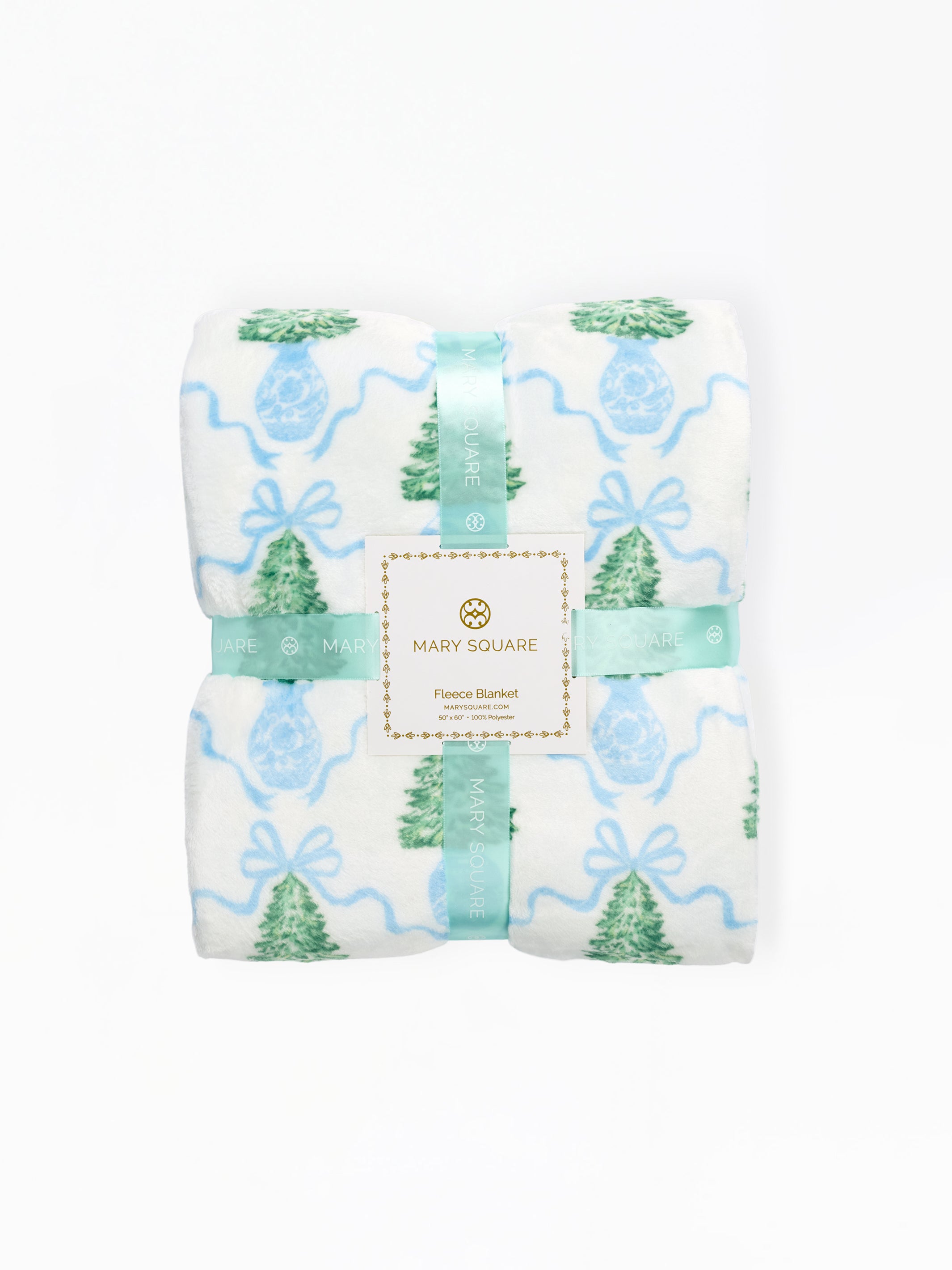 A folded Mary Square flannel blanket with a festive holiday print, featuring green pine trees, blue ornaments, and light blue wavy lines on a white background, wrapped in a matching mint green ribbon with a central brand label.