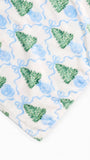 A close-up of a soft fabric product, likely a blanket or throw, featuring a repeating pattern of green Christmas trees, blue ornaments, and wavy blue lines on an off-white background.