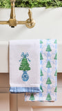 Two decorative kitchen towels hanging over a white sink. One towel is white with an embroidered green Christmas tree in a blue vase with a blue bow.