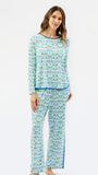 A woman modeling a matching two-piece pajama set with a light blue and green floral pattern and solid blue trim, photographed against a plain white studio background.