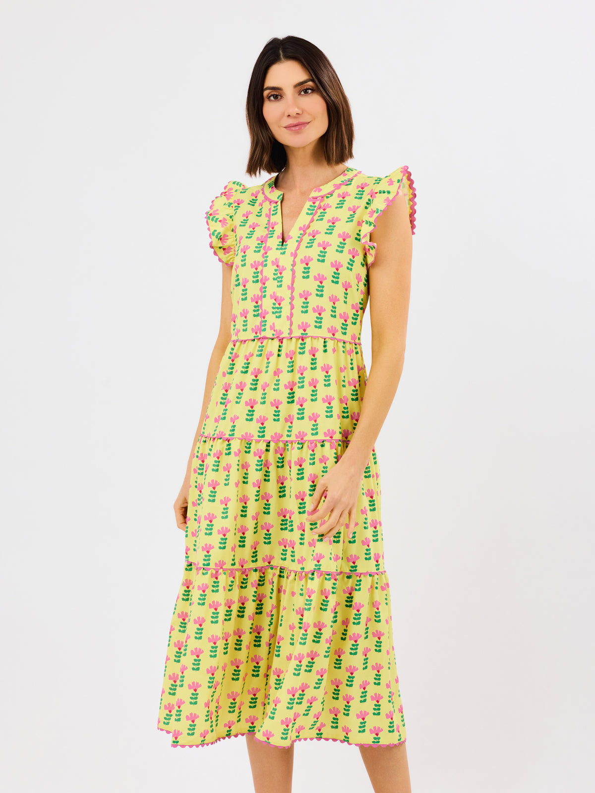 Woman wearing a yellow dress with pink floral pattern on a white background
