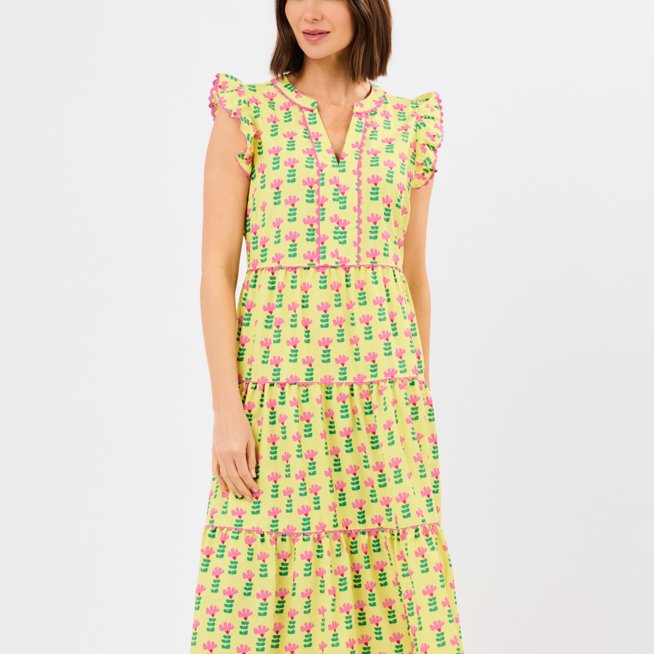 Woman wearing a yellow dress with pink floral pattern on a white background