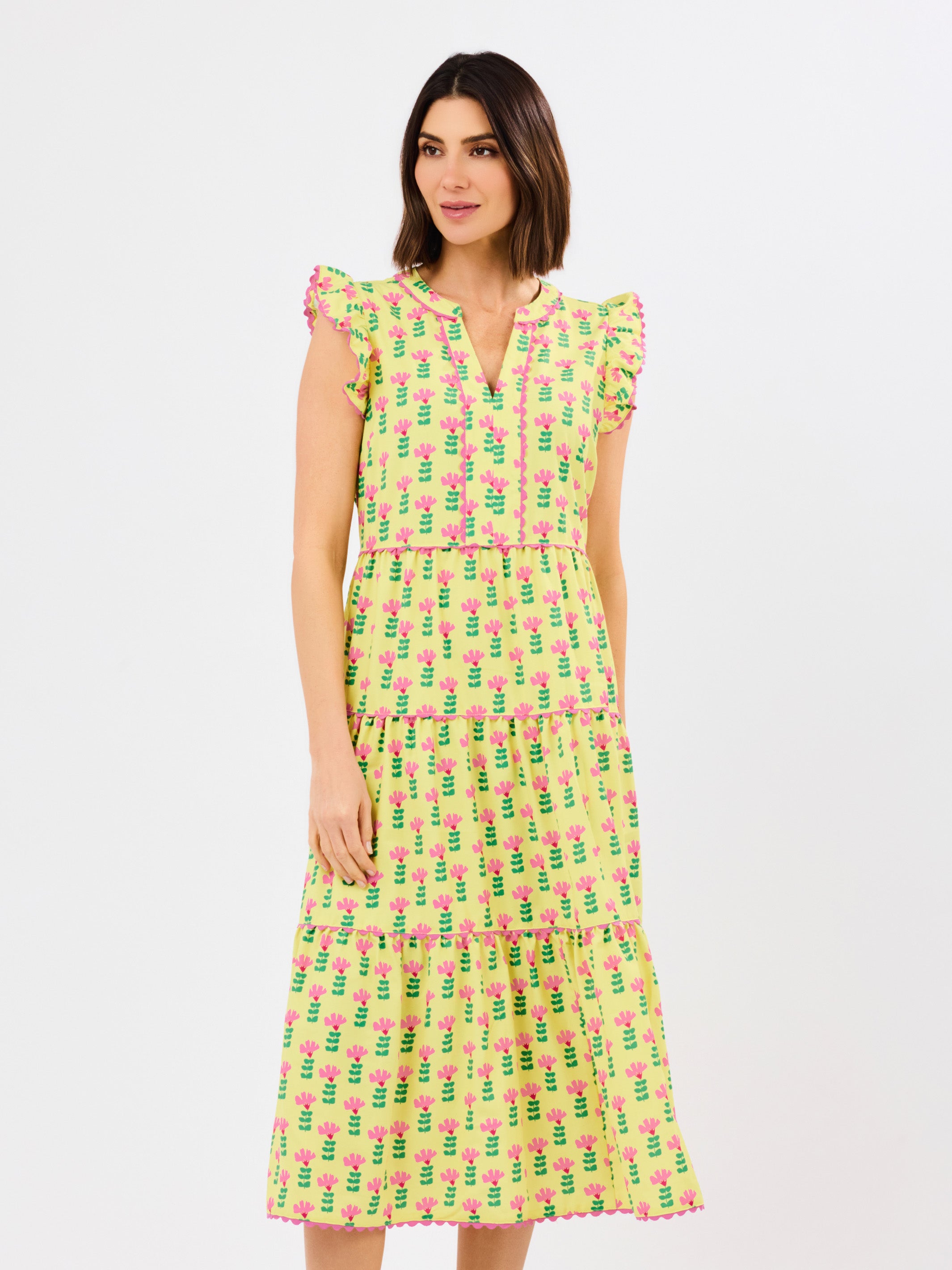 Woman wearing a yellow dress with pink floral pattern on a white background