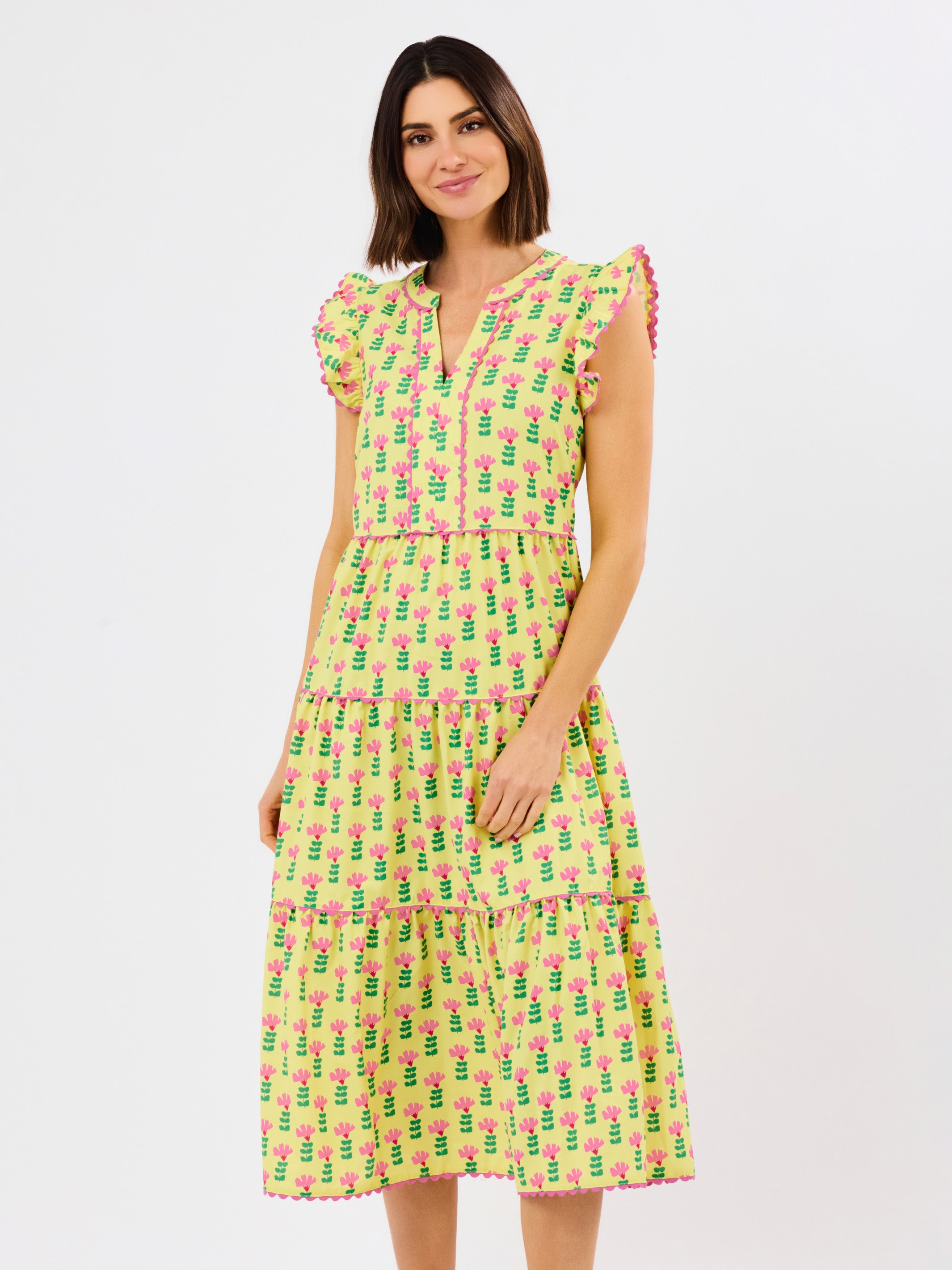 Woman wearing a yellow dress with pink floral pattern on a white background