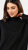A woman wearing a black long-sleeve turtleneck top, shown from the chest up against a plain light background.