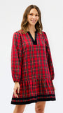 A woman modeling a red and black plaid long-sleeve nightgown or tunic dress with a black V-neck trim, set against a plain white studio background.