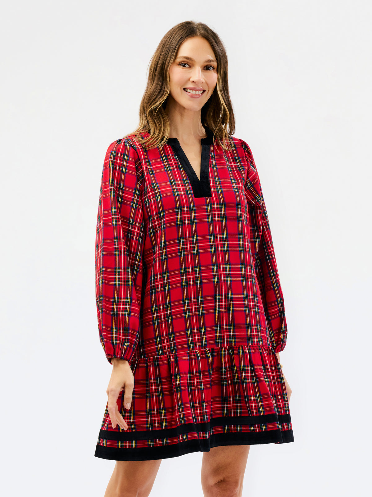 A woman modeling a red and black plaid long-sleeve nightgown or tunic dress with a black V-neck trim, set against a plain white studio background.