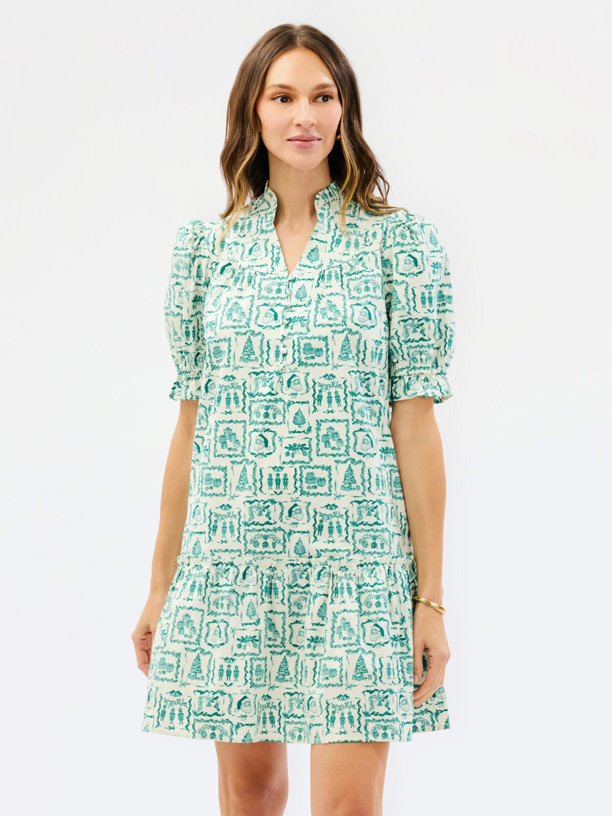 A woman modeling a short-sleeve V-neck dress with puff sleeves and an allover green and white architectural block print, set against a plain white studio background.