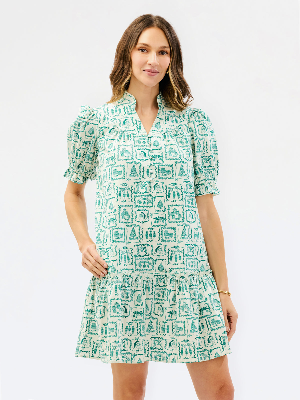 A woman modeling a short-sleeve V-neck dress with puff sleeves and an allover green and white graphic print, set against a plain white studio background.