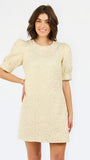 A woman modeling a short-sleeve cream lace dress with puff sleeves and a round neckline, photographed against a plain white studio background.