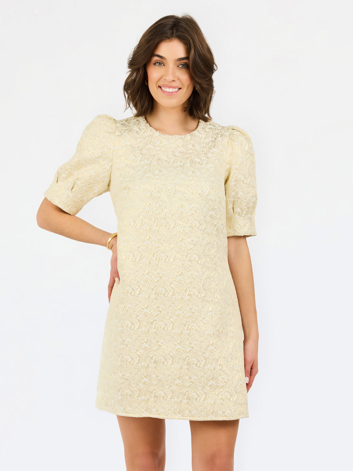 A woman modeling a short-sleeve cream lace dress with puff sleeves and a round neckline, photographed against a plain white studio background.