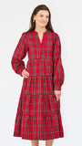A woman modeling a red tartan plaid midi dress with tiered ruffles, long sleeves, and a split neckline, set against a plain white studio background.