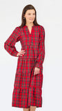 A woman modeling a red and black tartan plaid midi dress with long sleeves, a split neckline, and a tiered skirt, set against a plain white studio background.