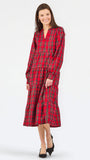 A woman modeling a red tartan plaid midi dress with long sleeves and a tiered skirt, paired with black heels, against a plain white studio background.