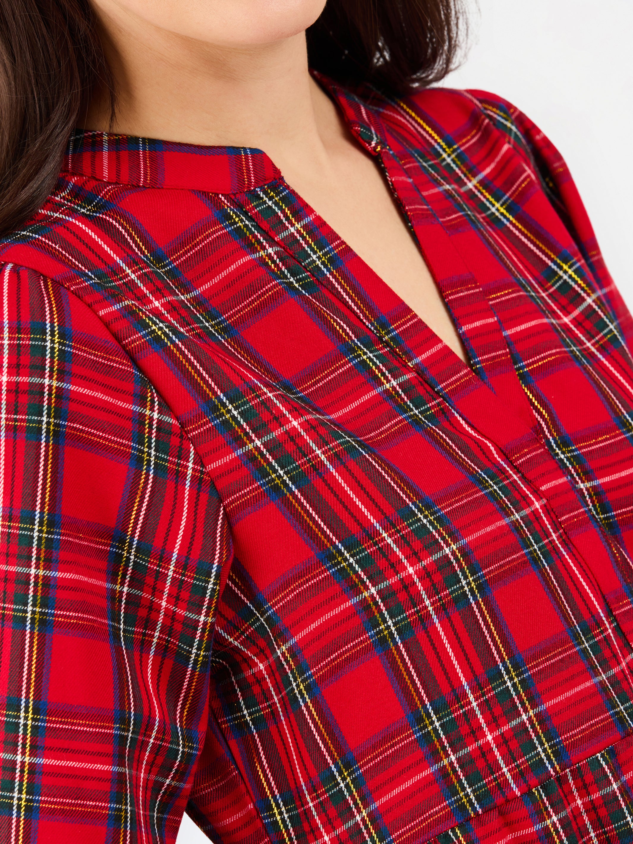 Close-up of a red tartan plaid top with a split V-neckline, worn by a model.