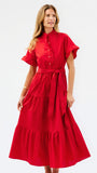A woman modeling a bright red midi dress with short flutter sleeves, a buttoned stand collar, a matching waist tie, and a tiered skirt, photographed against a plain white studio background.