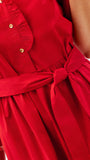 Close-up of a bright red dress with a tie waist belt and small gold buttons, shown on a model against a light background.