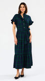 A woman modeling a dark green and black plaid midi dress with short flutter sleeves, a buttoned collar, and a matching waist tie, paired with black heels against a plain white studio background.