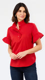 A woman modeling a bright red short-sleeve blouse with a high mock neck, button placket, and ruffled sleeves, paired with dark blue jeans against a plain white studio background.