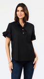 A woman modeling a black short-sleeve button-up blouse with ruffled sleeves and gold buttons, paired with dark blue jeans, against a plain white studio background.
