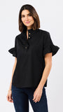 A woman modeling a black short-sleeve blouse with ruffled trim and gold buttons, paired with dark blue jeans, against a plain light gray studio background.