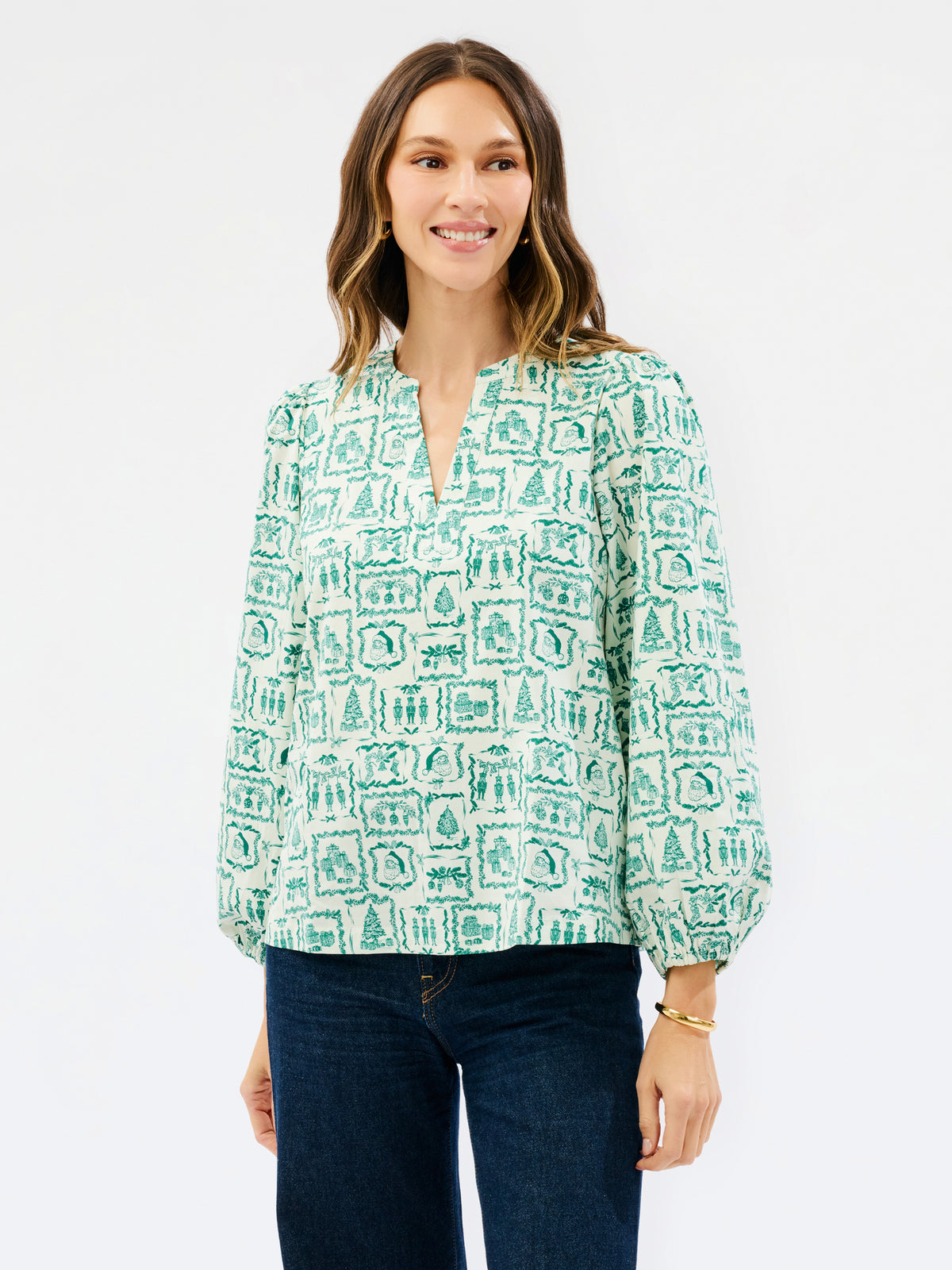 Brown haired woman wearing a white blouse with santa and other christmas icons on it 