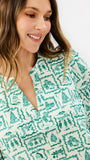 Brown haired woman wearing a white blouse with santa and other christmas icons on it 