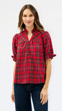 A woman modeling a red plaid short-sleeve blouse with a gathered chest detail and dark blue jeans, set against a plain white studio background.