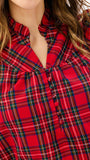 A close-up of a red plaid button-up shirt worn by a model, showing the chest area with a gathered ruffle detail at the collar and front buttons.