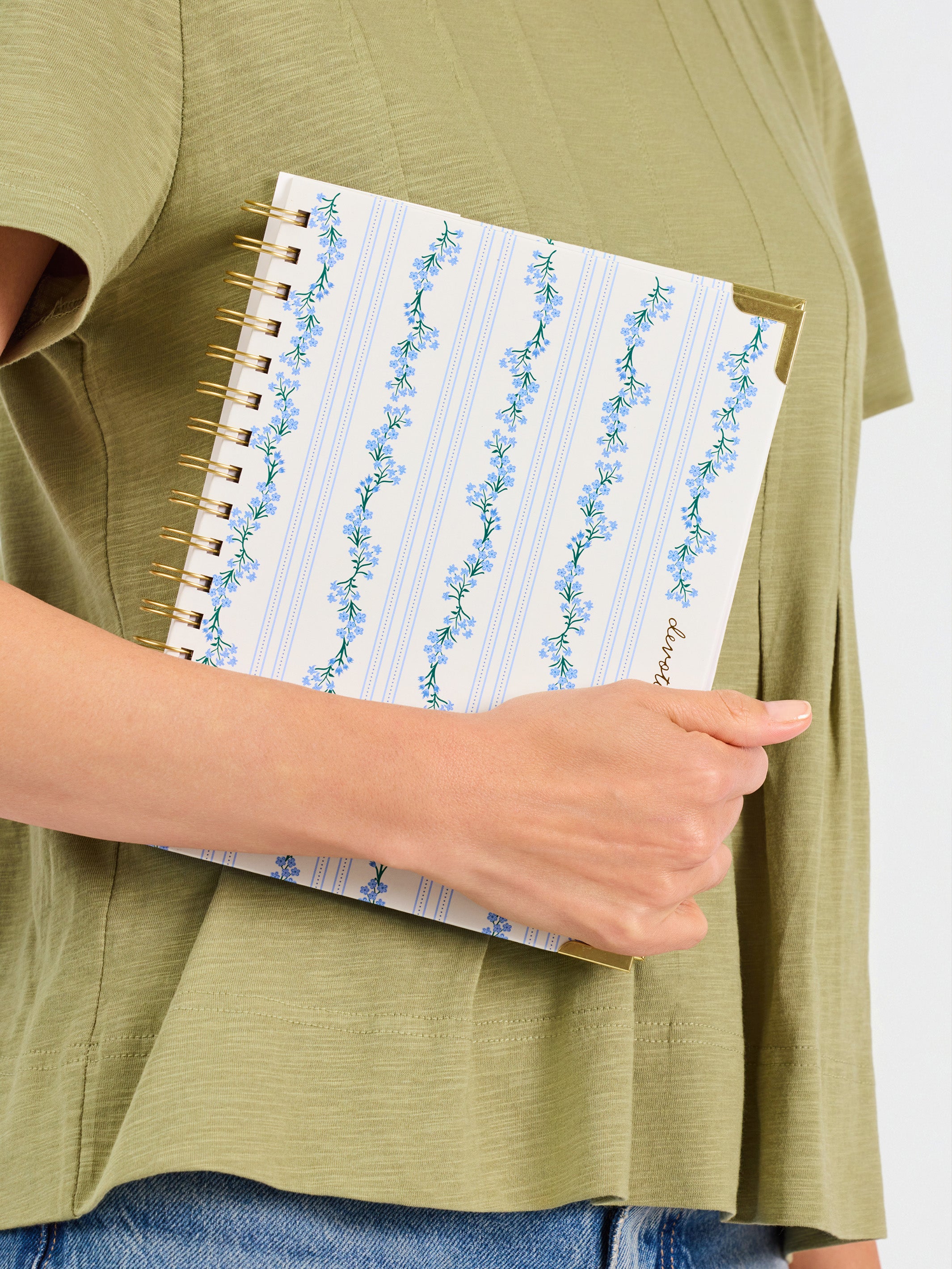 Person holding a spiral-bound notebook with floral design on the cover