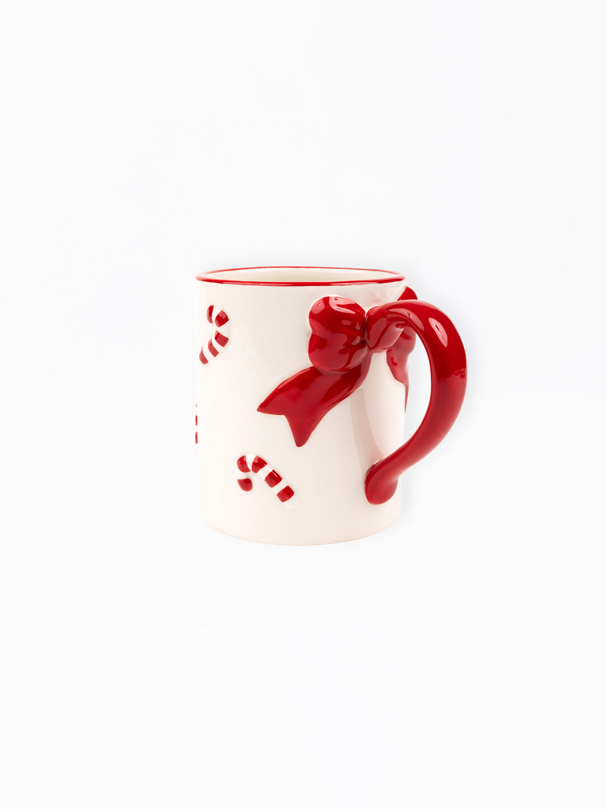A white ceramic mug with a glossy red handle shaped like a bow, red rim, and red candy cane cutouts on the side, shown against a plain white background.