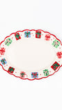 An oval white serving platter with a scalloped edge, decorated with a border of colorful gift boxes and red dots.
