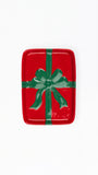 A rectangular red tray with rounded corners, decorated to look like a wrapped gift with a green ribbon and bow, shown on a plain white background.
