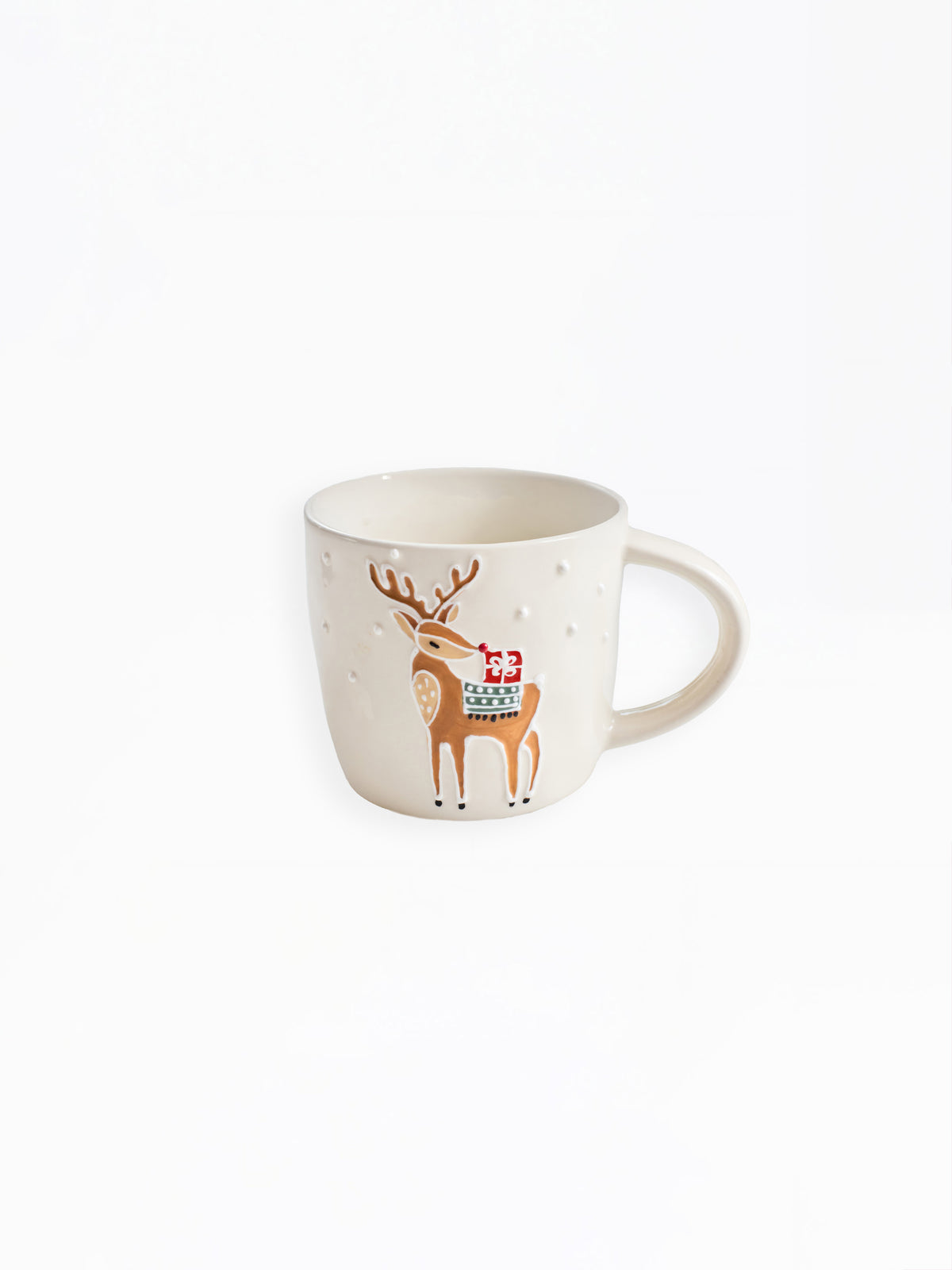 A cream-colored ceramic mug featuring a brown reindeer illustration wearing a red Santa hat and a green patterned scarf, set against a plain white background.