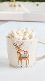 A cream-colored ceramic mug with a brown deer design wearing a red Santa hat, filled with mini marshmallows on a white countertop.