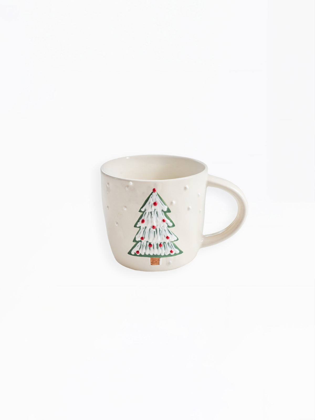 An off-white ceramic mug featuring a hand-painted Christmas tree with green branches, white ornaments, and red lights, set against a plain white background.