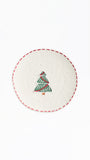 A round white ceramic plate featuring a hand-painted green Christmas tree with red stripes and a red dashed rim, shown against a plain white background.