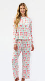 A woman modeling a matching two-piece pajama set with a long-sleeve top and wide-leg pants, featuring an all-over repeating bow pattern in red, green, and blue on a white background.