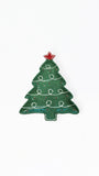 A Christmas tree shaped enamel pin in dark green with white decorative swirls, a red star topper, and small red and gold accents, shown on a plain white background.