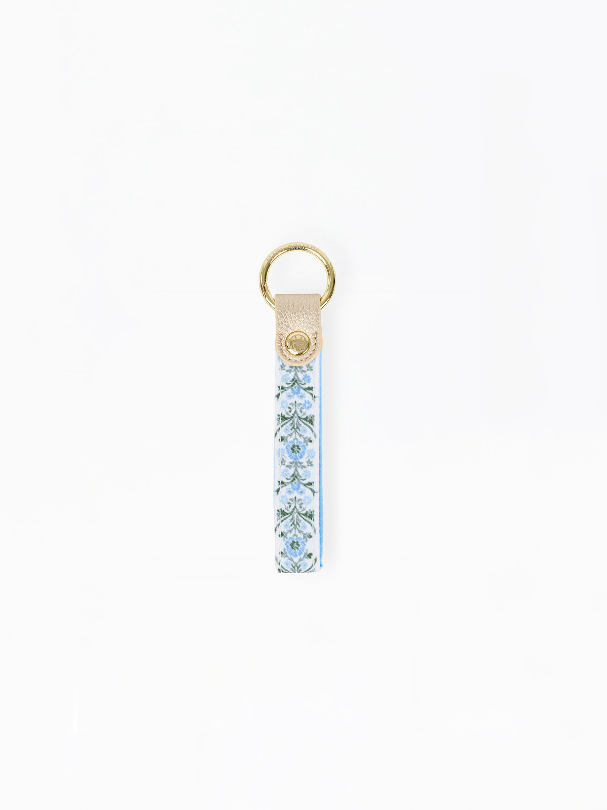 A vertical leather keychain strap featuring a light blue and white floral pattern, finished with a gold-tone metal ring and a small gold logo medallion on the leather tab.