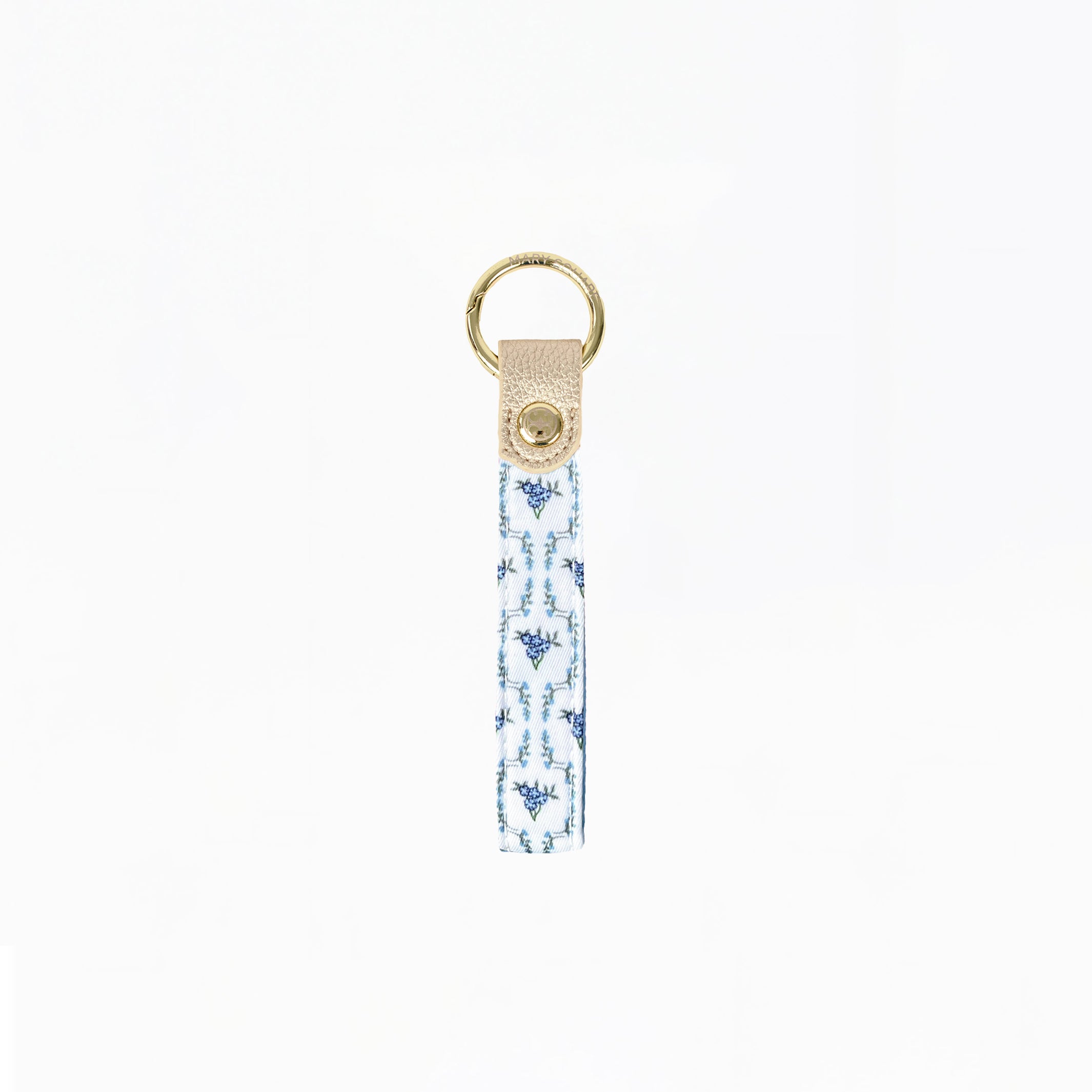 A fabric keychain strap featuring a blue and white ikat pattern, finished with a beige leather tab and a gold-tone metal key ring.