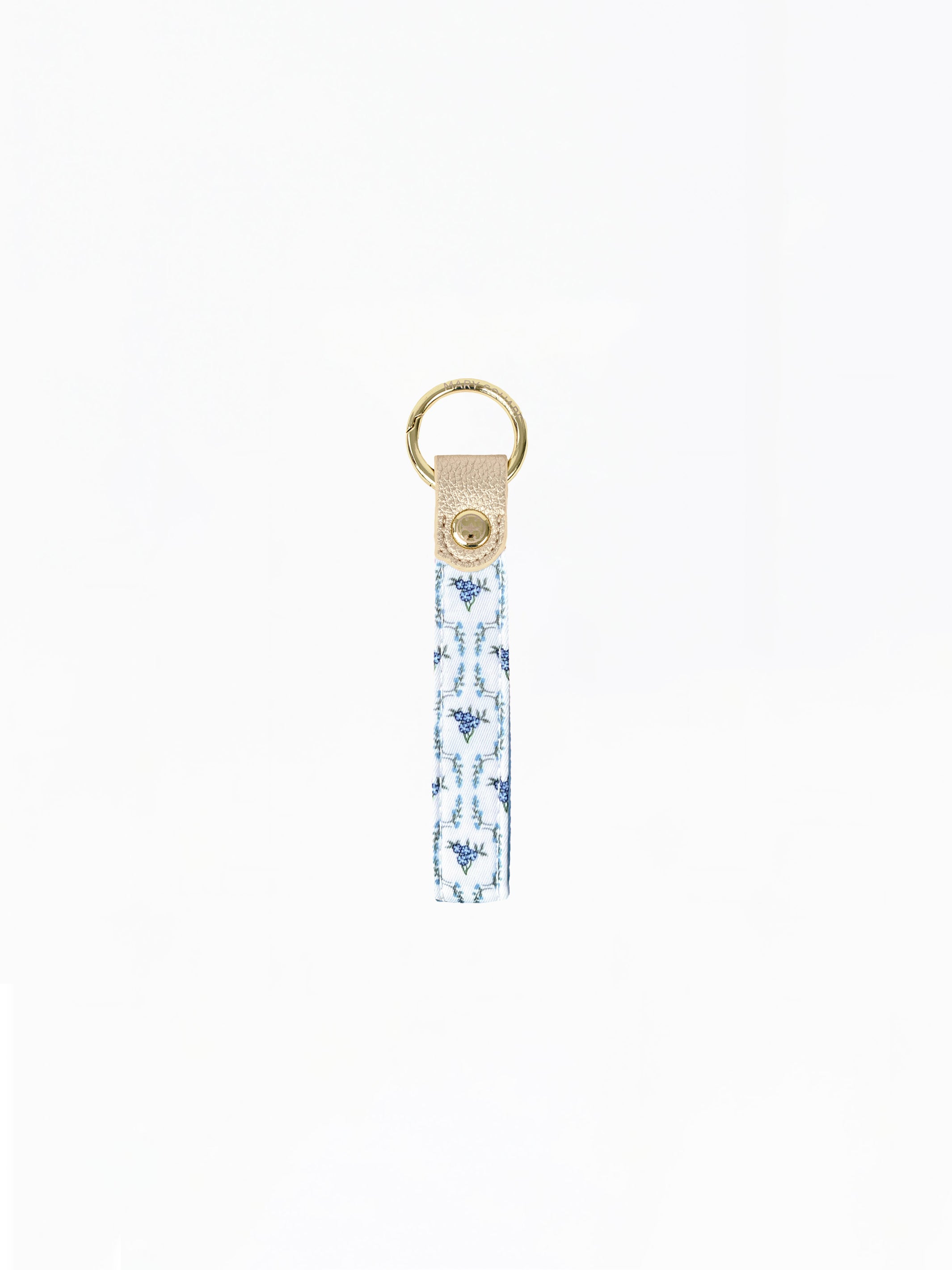 A fabric keychain strap featuring a blue and white ikat pattern, finished with a beige leather tab and a gold-tone metal key ring.
