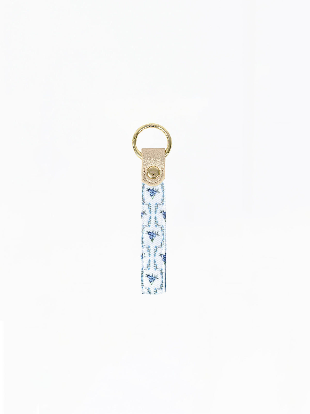 A fabric keychain strap featuring a blue and white ikat pattern, finished with a beige leather tab and a gold-tone metal key ring.