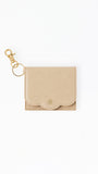 A small beige textured leather card holder with a gold-tone clasp and key ring, shown on a plain white background.