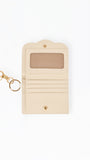 A cream-colored leather card holder wallet with a gold-tone keychain clasp, shown on a plain white background.